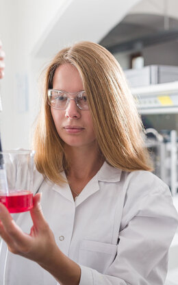 Eine Studentin mit einer Pipette und einem Becherglas mit Flüssigkeit in einem Labor an der TH Aschaffenburg.